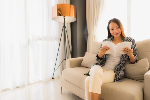 Retrato hermosas mujeres asiáticas jóvenes leyendo un libro y sentado en el sillón