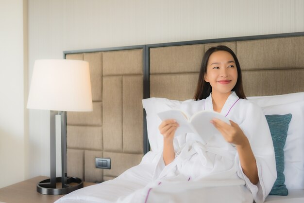 Retrato hermosas mujeres asiáticas jóvenes con libro sobre la cama