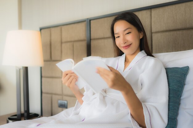 Retrato hermosas mujeres asiáticas jóvenes con libro sobre la cama