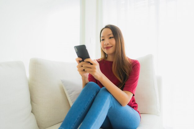 Retrato hermosas mujeres asiáticas jóvenes con teléfono móvil o inteligente en el sofá