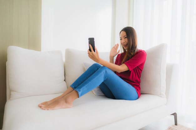 Retrato hermosas mujeres asiáticas jóvenes con teléfono móvil o inteligente en el sofá