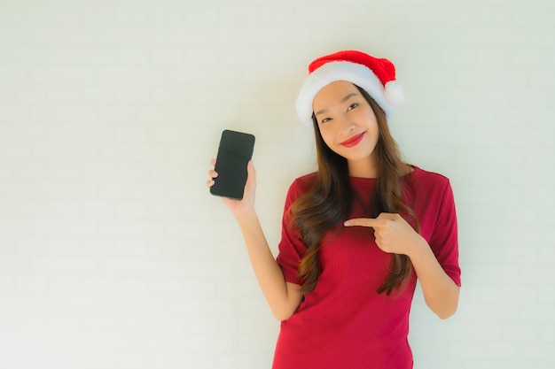 Retrato hermosas mujeres asiáticas jóvenes usan sombrero de Navidad de santa con teléfono móvil