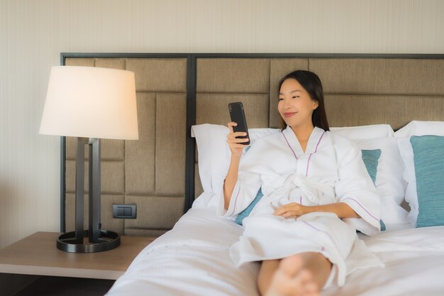 Retrato hermosas mujeres asiáticas jóvenes usando el móvil en la cama