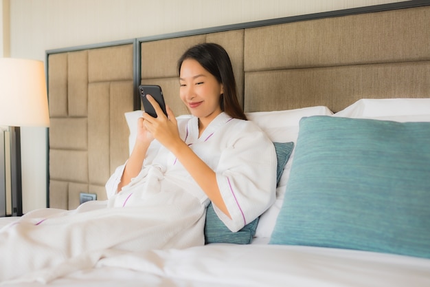 Retrato hermosas mujeres asiáticas jóvenes usando el móvil en la cama