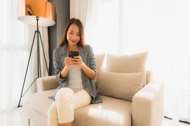 Retrato hermosas mujeres asiáticas jóvenes usando teléfono móvil hablando y sentado en el sillón