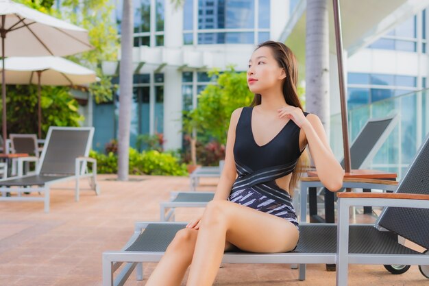 Retrato hermoso joven mujer asiática ocio relajarse sonreír alrededor de la piscina al aire libre para vacaciones