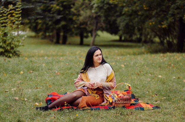 Retrato hermoso de la muchacha del otoño. Mujer Joven Posando Sobre Hojas Amarillas En El Parque De Otoño. Al aire libre