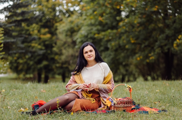 Retrato hermoso de la muchacha del otoño. Mujer Joven Posando Sobre Hojas Amarillas En El Parque De Otoño. Al aire libre