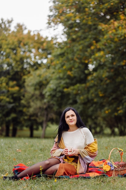 Retrato hermoso de la muchacha del otoño. mujer joven posando sobre hojas amarillas en el parque de otoño. al aire libre