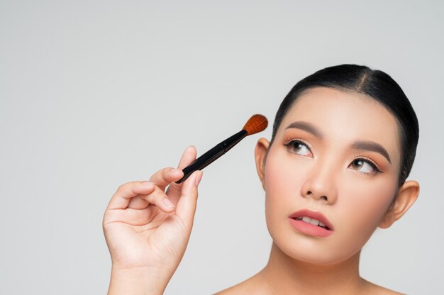 Retrato, de, hermoso, mujer asiática, tenencia, maquillaje, colorete, cepillo