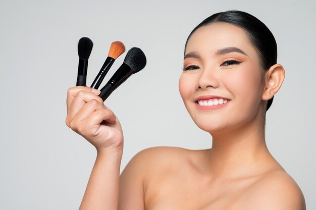 Retrato, de, hermoso, mujer asiática, tenencia, maquillaje, colorete, cepillo