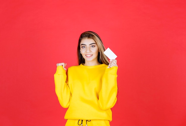 Retrato, de, hermoso, mujer joven, con, tarjeta de visita en blanco, posición