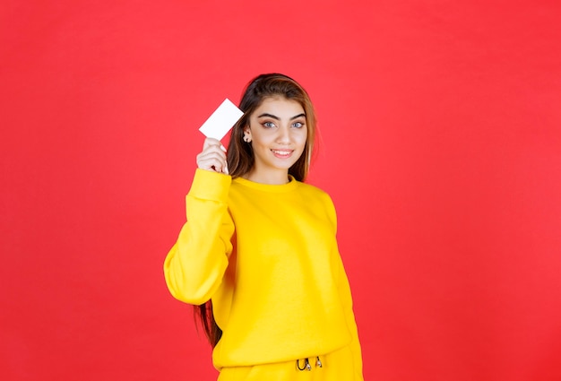 Retrato, de, hermoso, mujer joven, con, tarjeta de visita en blanco, posición