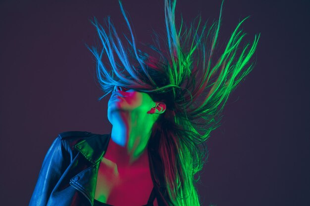 Retrato hermoso de la mujer con el pelo que sopla en la luz de neón colorida