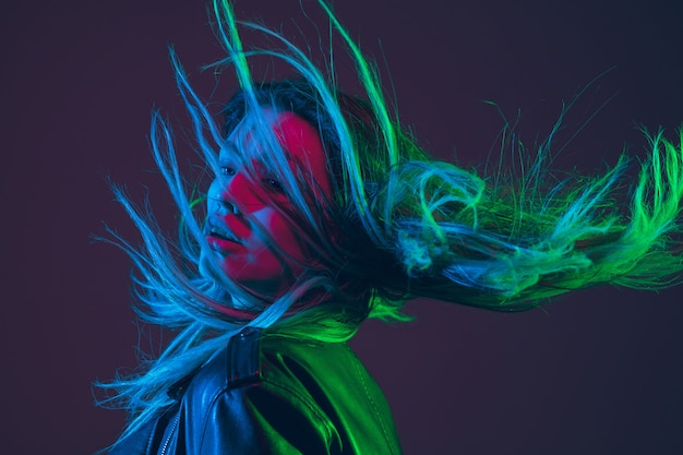 Retrato hermoso de la mujer con el pelo que sopla en la luz de neón colorida