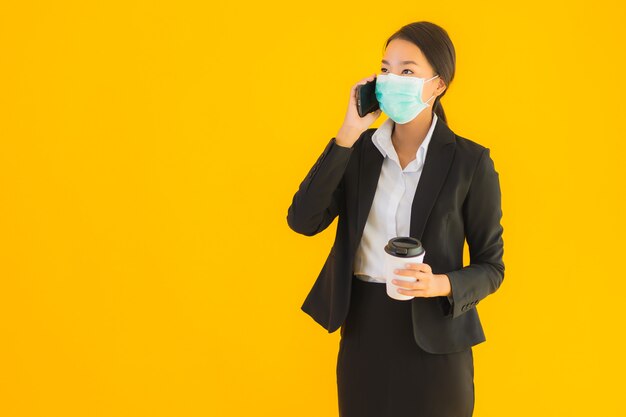 Retrato hermoso negocio joven mujer asiática usar máscara usar teléfono móvil con café