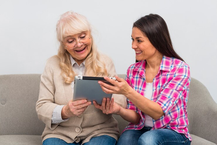 Foto gratuito retrato de hija alegre mostrando tableta digital a su madre senior