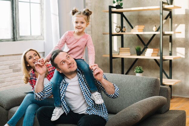 Retrato de hija feliz sentada en el hombro de su padre con su madre