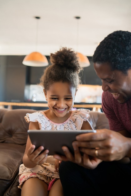 Retrato de una hija y un padre usando una tableta digital mientras se queda en casa