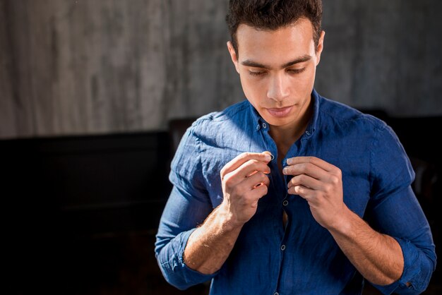 Retrato de un hombre abotonando su camisa azul