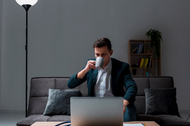 Retrato de hombre adulto disfrutando de un café mientras trabajaba de noche