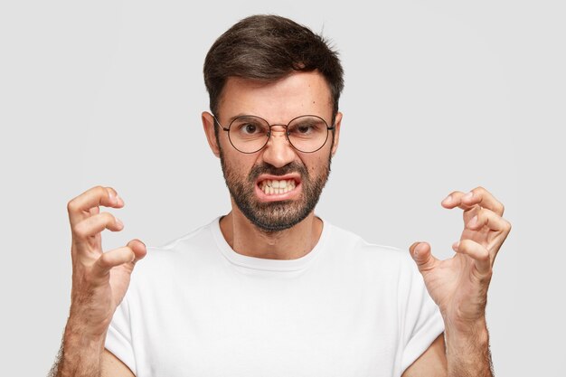 Retrato de hombre sin afeitar emocionado molesto irritado aprieta los dientes y gesticula con enojo mientras discute con su esposa