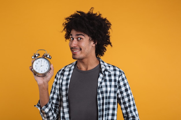 Foto gratuita retrato de un hombre africano feliz sonriente que muestra el despertador