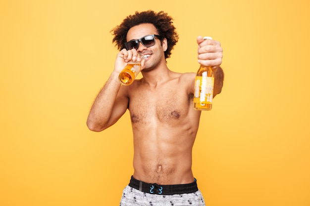 Retrato de un hombre africano en gafas de sol que muestra la botella de cerveza