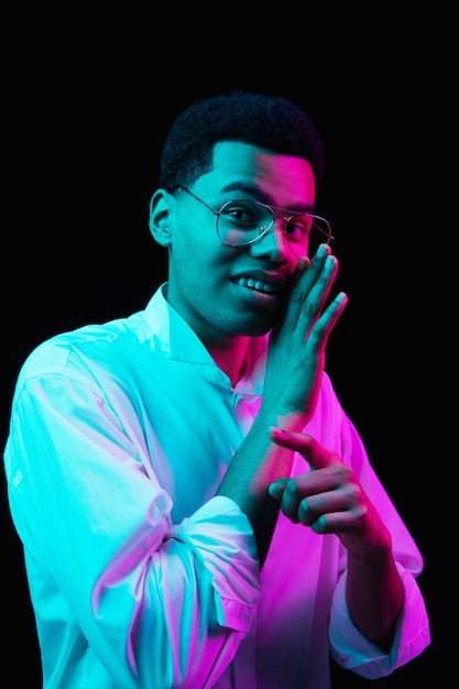 Retrato de un hombre afroamericano aislado en un estudio negro con luz de neón multicolor