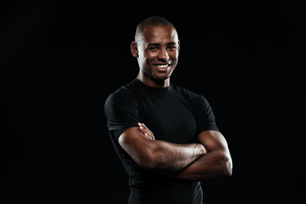 Retrato de hombre afroamericano deportivo sonriente con los brazos cruzados mirando a la cámara