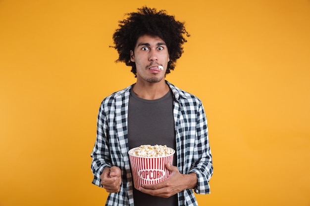 Retrato de un hombre afroamericano divertido comiendo palomitas de maíz