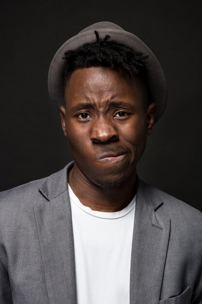 Retrato de un hombre afroamericano de moda sonriendo sobre fondo negro. Un buen tipo con una chaqueta gris y una camiseta blanca sobre un fondo oscuro de estudio. un gran retrato