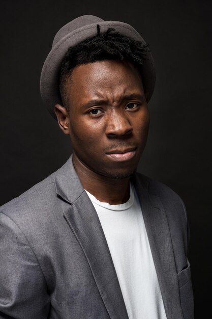 Retrato de un hombre afroamericano de moda sonriendo sobre fondo negro. Un buen tipo con una chaqueta gris y una camiseta blanca sobre un fondo oscuro de estudio. un gran retrato