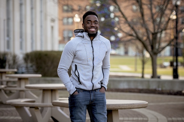 Retrato de un hombre afroamericano sonriente en un parque bajo la luz del sol con un fondo borroso