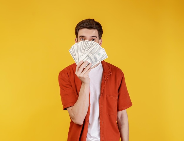 Retrato de un hombre alegre con billetes de dólar sobre fondo amarillo