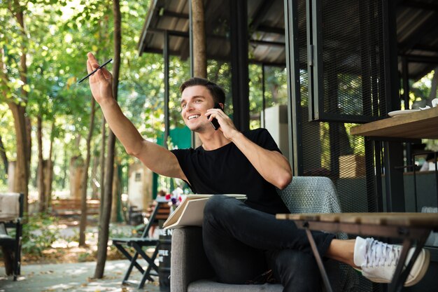 Retrato de un hombre alegre feliz hablando por teléfono móvil