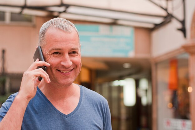 Retrato del hombre alegre que habla en el teléfono.