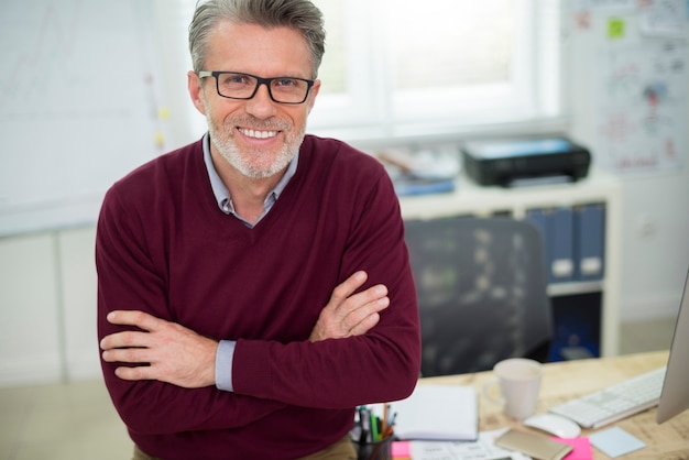 Retrato de hombre alegre sentado en el escritorio