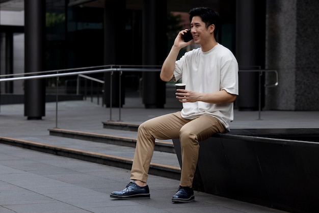 Retrato de hombre asiático guapo con smartphone al aire libre en la ciudad