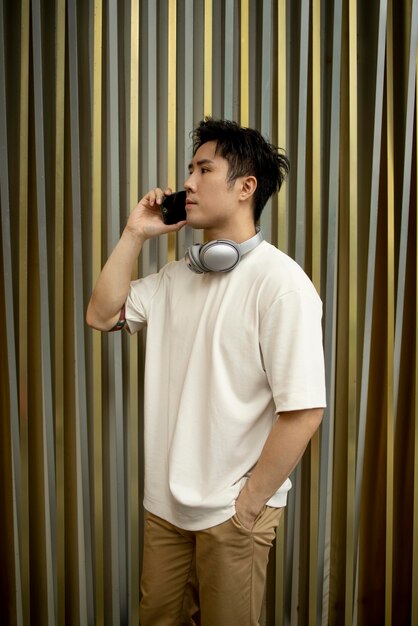 Retrato de hombre asiático guapo con smartphone y auriculares al aire libre