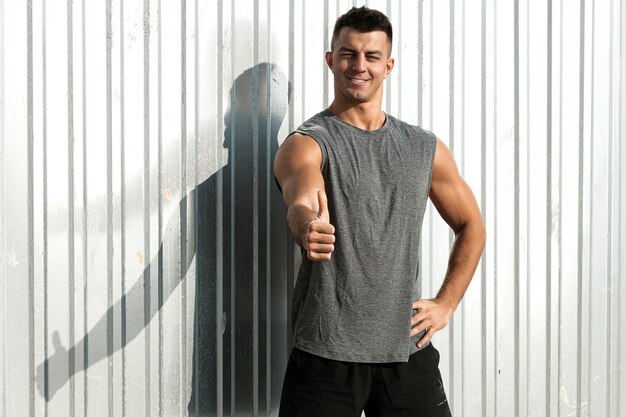 Retrato de hombre de atleta de fitness con el pulgar hacia arriba gesto. Buen hombre de musculatura.