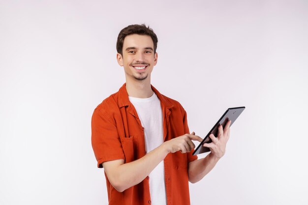 Retrato de un hombre atractivo y alegre que usa una aplicación de dispositivo que busca en la web aislada sobre un fondo de color blanco