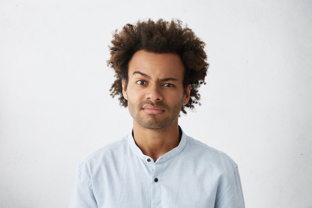 Foto gratuita retrato de hombre atractivo de raza mixta disgustado con oscuros ojos estrechos y cabello rizado y espeso