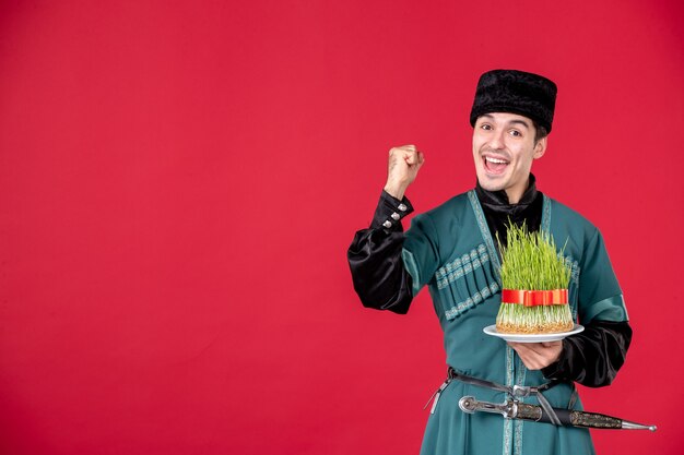 Retrato de hombre azeri en traje tradicional sosteniendo semeni studio shot en rojo novruz primavera concepto color de ejecutante