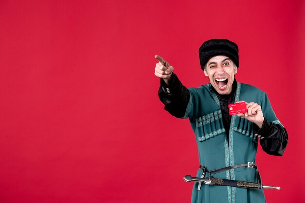 Retrato de hombre azeri en traje tradicional sosteniendo tarjeta de crédito apuntando studio shot rojo dinero novruz primavera étnica