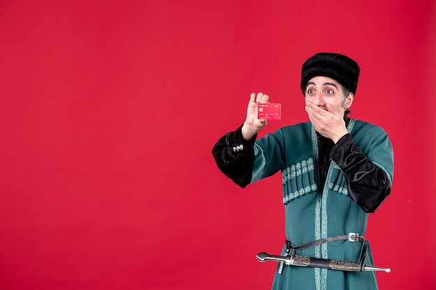 Foto gratuita retrato de hombre azeri en traje tradicional con tarjeta de crédito studio shot rojo étnico primavera novruz