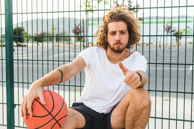 Retrato de un hombre con baloncesto gesticular pulgar arriba