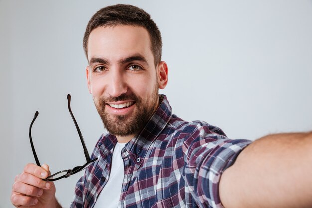 Retrato de hombre con barba en camisa haciendo selfie
