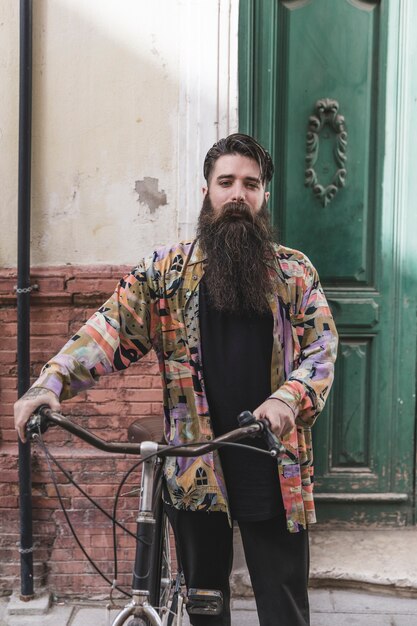 Retrato de un hombre de barba con su bicicleta mirando a cámara