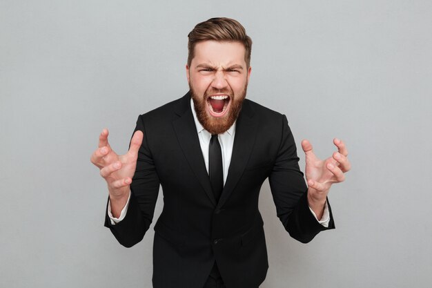 Retrato de un hombre barbudo enojado en traje gritando